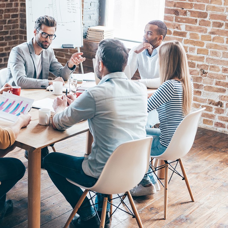 Everyday meeting. Group of six young people discuss something and gesturing while sitting at the table in office