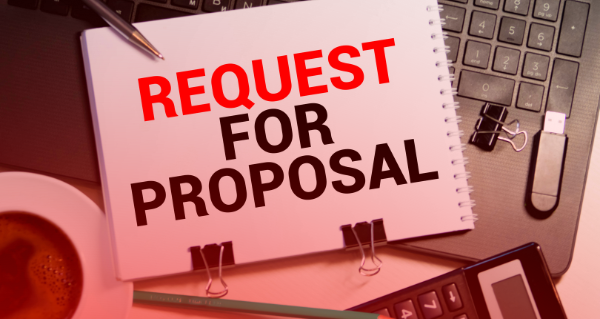 Request for Proposal (RFP) displayed in block capitals on a notepad alongside other office equipment. 